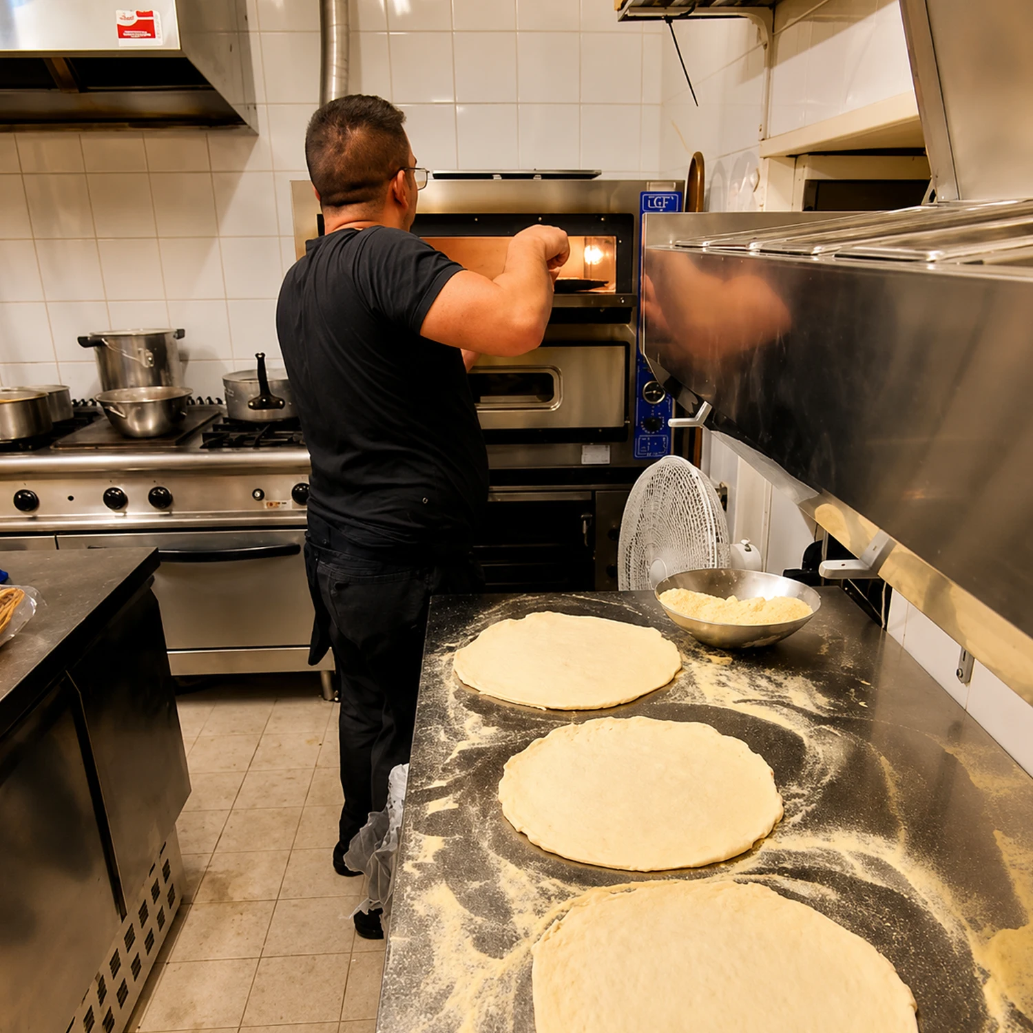 Bartolomeo étire la pâte à pizza en cuisine